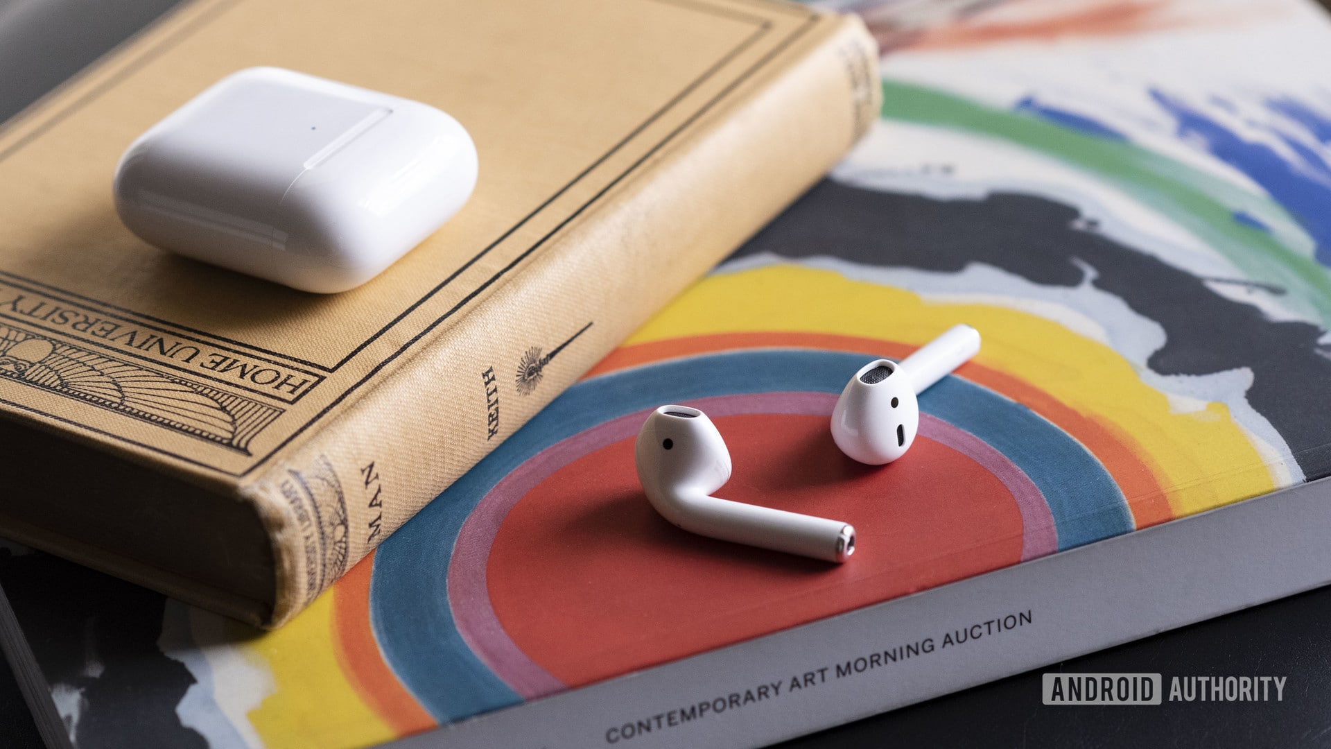 Apple AirPods (2nd generation) earbuds case separate Apple new AirPods 2 outside of the case resting on a book.