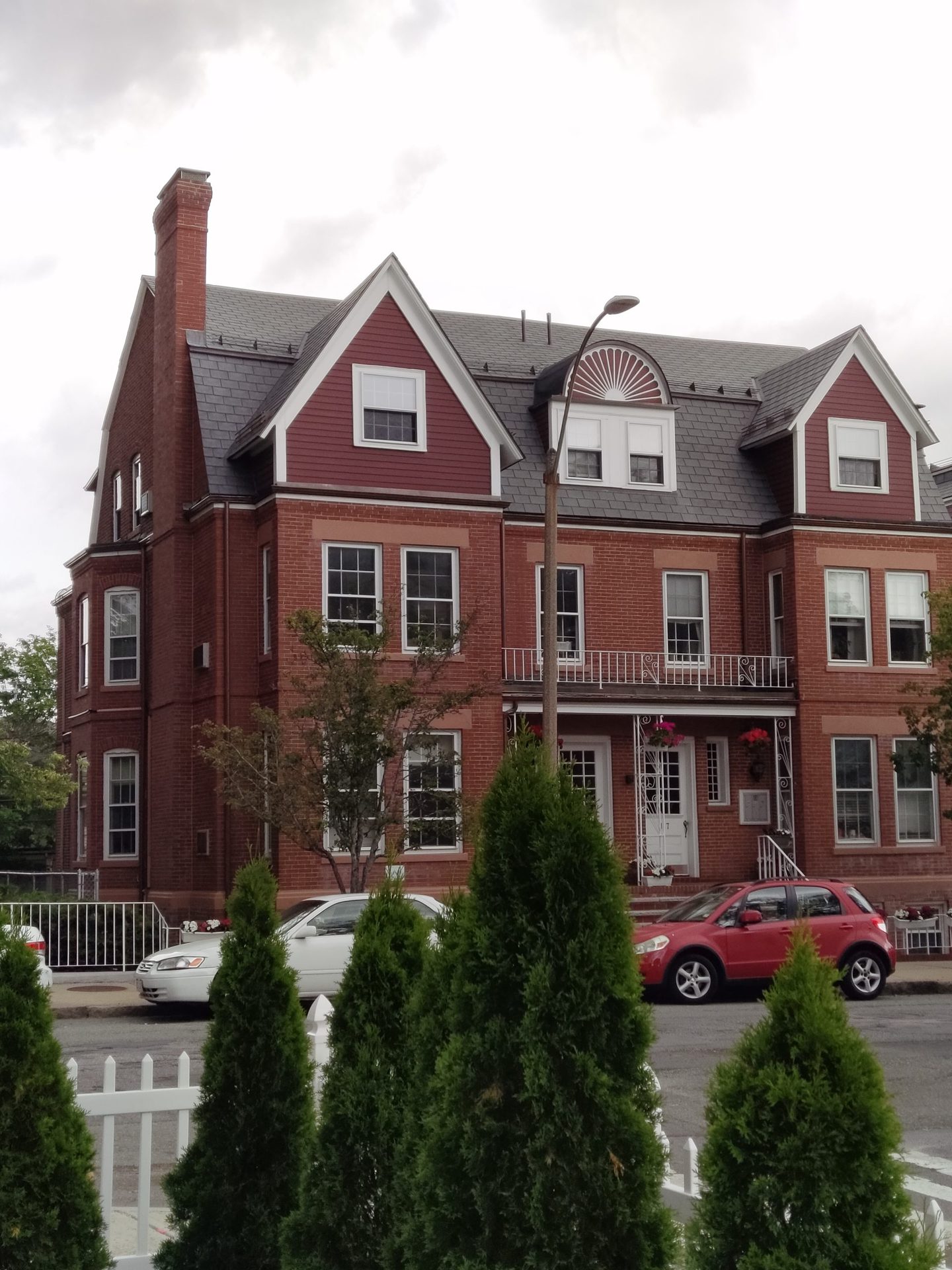 TCL 20 Pro 5G Telephoto Camera shot of the exterior of a house, with two cars parked outside and trees in the foreground.