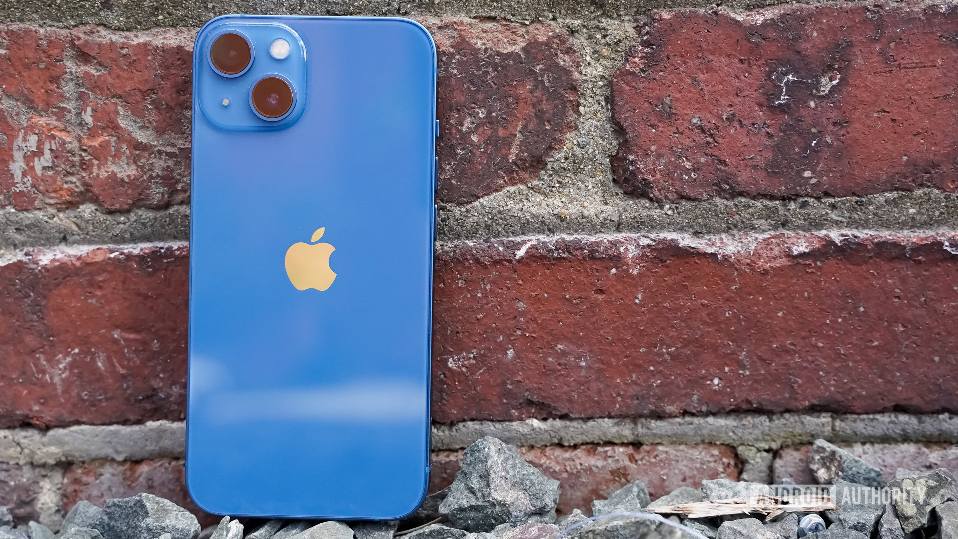Apple iPhone 13 left centered rear against red brick wall Apple iPhone 13 left centered rear against red brick wall