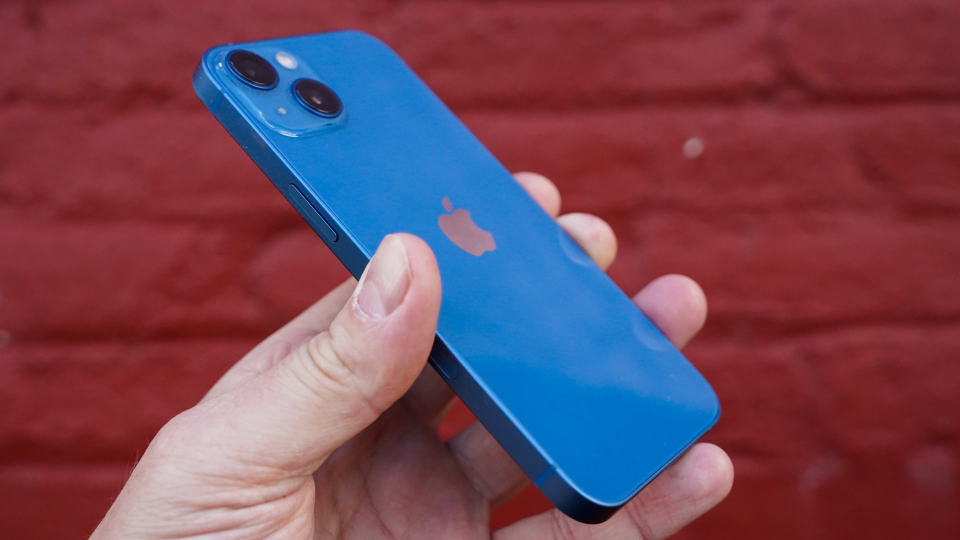 Apple iPhone 13left rear profile against red brick wall Apple iPhone 13 left rear profile against red brick wall