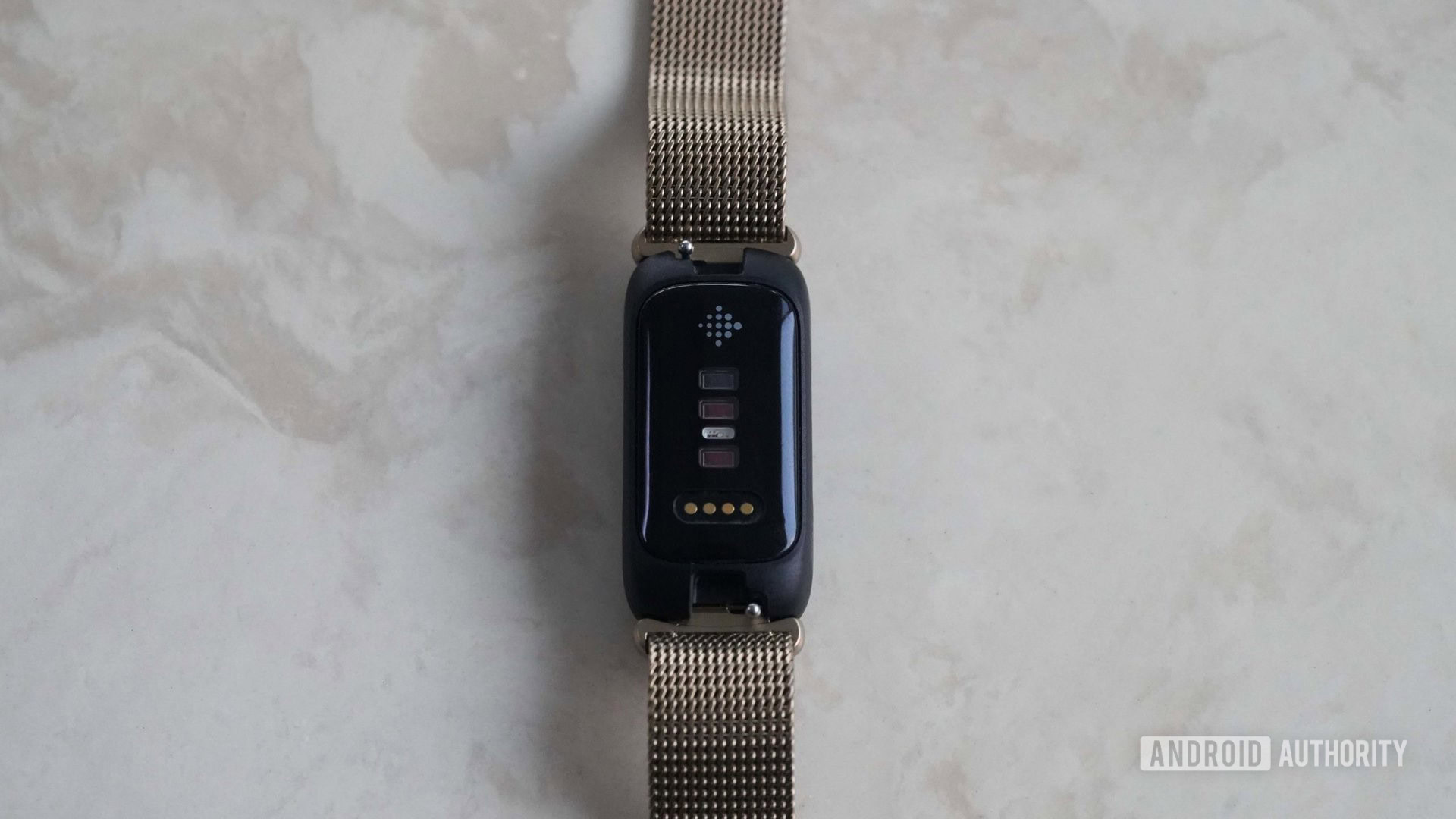 A Fitbit Inspire 3 rests face down highlighting the device's sensors.