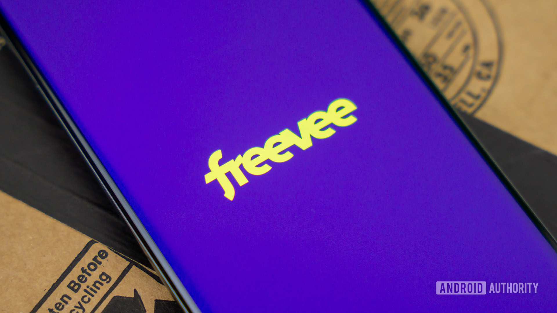 Stock photo of Freevee by Amazon logo on phone next to box 3 Stock photo of Freevee by Amazon logo on phone next to box 3