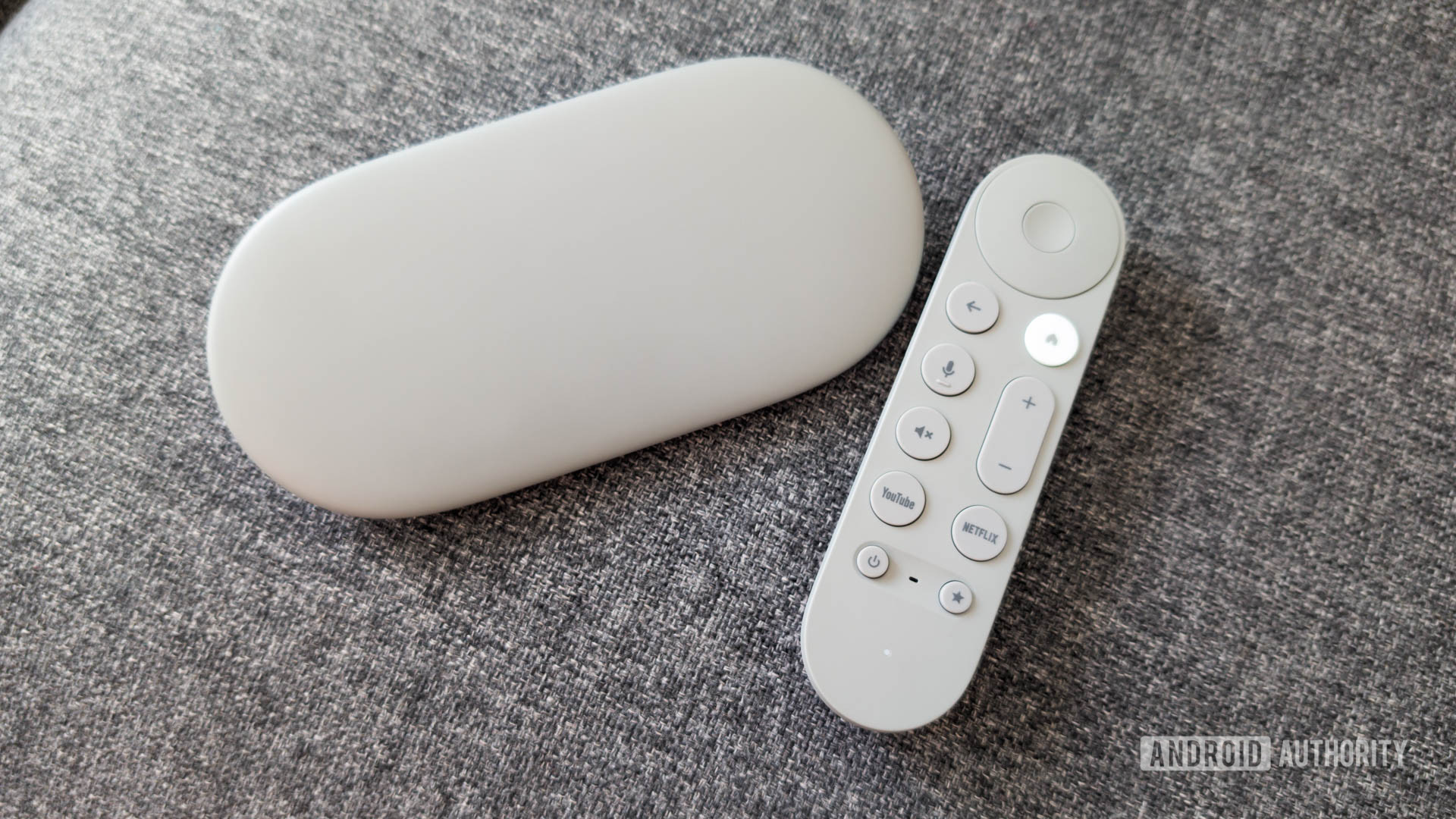 Google TV Streamer with remote on couch Google TV Streamer with remote on couch